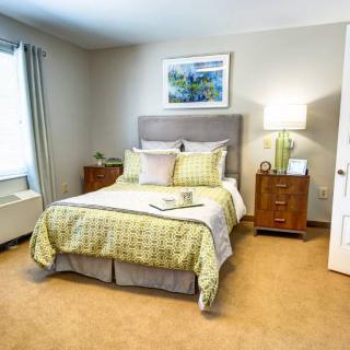 A cozy bedroom with a neatly made bed, nightstands, and soft lighting.