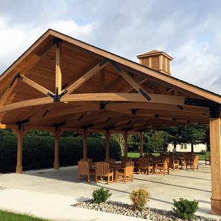 A wooden pavilion with outdoor seating under a clear sky.