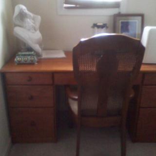 A home office with a wooden desk, chair, and decorative items.