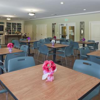 An empty dining area with tables and chairs, decorated with flowers.