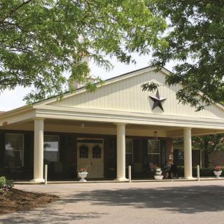A building entrance with columns and a star decoration, surrounded by trees.