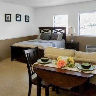 A minimalist bedroom with a cozy bed and a small dining area.