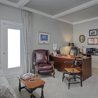 A cozy home office with a desk, chairs, and various decorations.