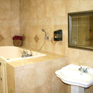 A bathroom featuring a bathtub, sink, and mirror with tile walls.
