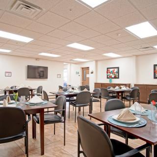 A well-lit dining room with neatly arranged tables and chairs, decorated with artwork on the walls.