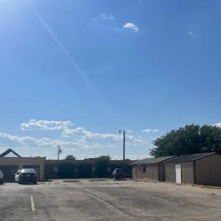 A sunny day at a quiet parking lot with clear skies and scattered clouds.