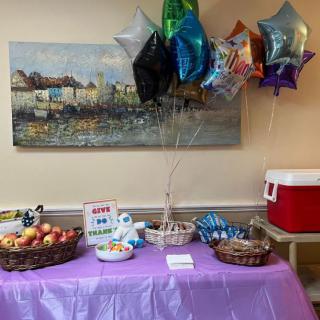 A festive table setup with snacks, fruits, and balloons in a decorated room.