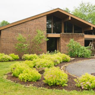 A modern brick house surrounded by lush greenery and well-maintained landscaping.