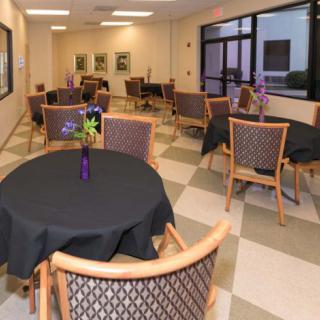 A cozy dining area with several tables and chairs, decorated with vases of flowers.