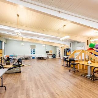 A spacious rehabilitation and therapy room equipped with various exercise machines and equipment.