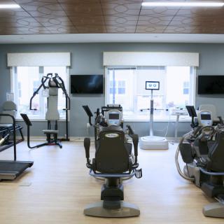 A well-lit gym interior with various exercise machines and fitness equipment.