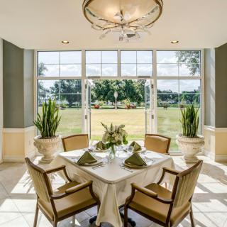 A beautifully set dining table in a well-lit room with large windows offering an expansive view of the outdoors.