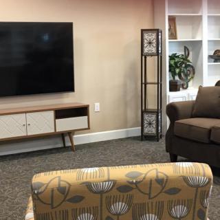 A cozy living room with a television, shelf, and comfortable seating.