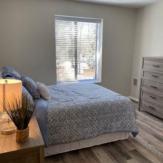 A cozy bedroom with a neatly made bed and a dresser by the window.