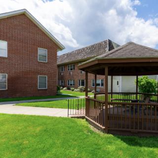 A peaceful outdoor area featuring a gazebo and well-maintained lawns surrounded by residential buildings.