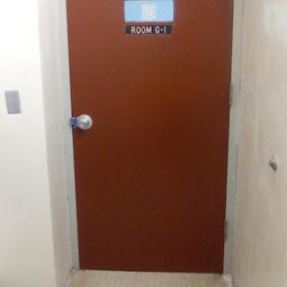 A closed brown door with a room number sign.