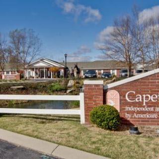A scenic view of a retirement home with a sign in the foreground and greenery surrounding the area.