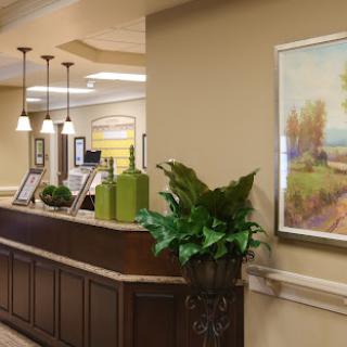 A welcoming lobby area featuring a reception desk, decorative plants, and framed artwork.