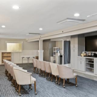 A modern conference room with rows of chairs and a projector screen.