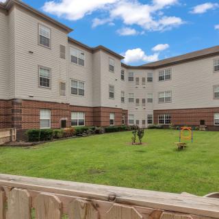 A residential building with a well-maintained lawn under a clear blue sky.