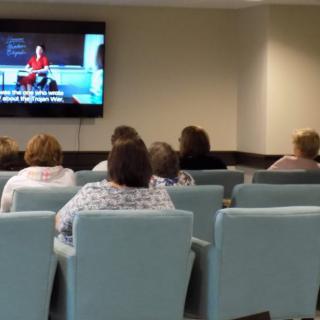 People seated in a waiting room watching television.