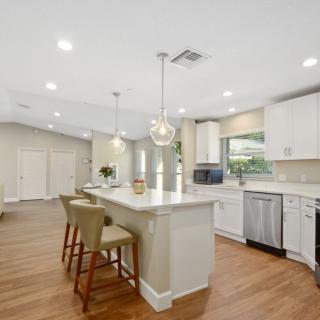 A spacious and modern kitchen with an island, white cabinets, and wood flooring.