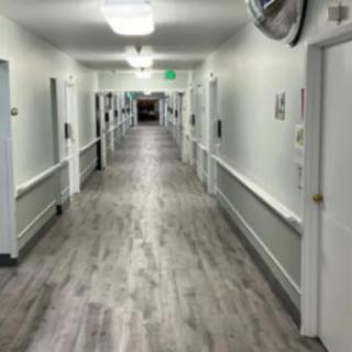 A long, well-lit hallway in a hospital with doors on either side.