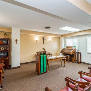 A small chapel interior with an altar, crosses, and seating area.