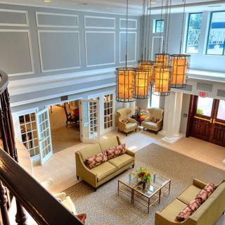 A spacious and elegantly designed living room with large sofas, a glass coffee table, and distinctive chandeliers.