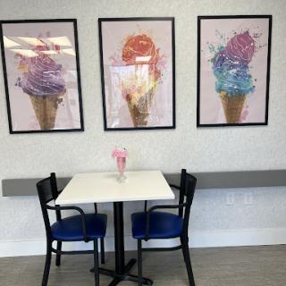 A cozy ice cream parlor featuring colorful cone artwork on the walls and a simple dining setup.