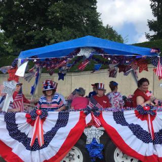 Participants celebrate with a festive float decorated in red, white, and blue for the parade.