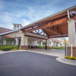 A modern building entrance with a covered driveway and well-maintained landscaping.