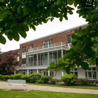 A brick building surrounded by lush greenery and framed by tree branches.
