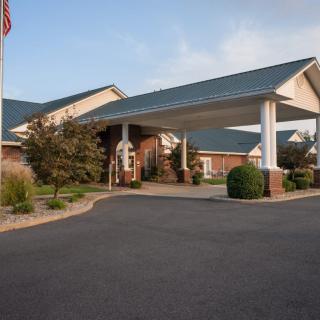 The image shows a building with a large covered entrance and well-maintained landscaping.