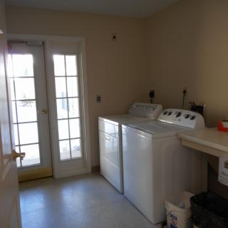 A well-lit laundry room featuring a washing machine and dryer next to a glass door.