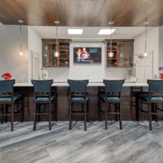 A modern bar area with sleek stools and a large TV on the wall.