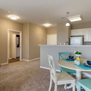 A modern open-concept living space featuring a dining area with turquoise accents and an adjacent kitchen.