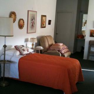 A cozy bedroom with a bed covered in an orange blanket, a sofa, and artwork on the walls.