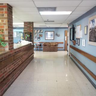 A view of a hospital corridor featuring a reception desk and artwork on the walls.