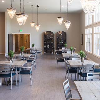 A modern dining area with sleek tables and chairs, illuminated by elegant chandeliers and natural light.