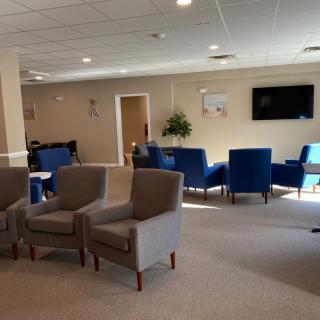 A spacious waiting room with comfortable seating and a television.