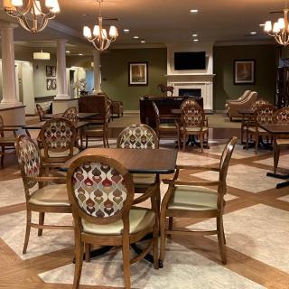 A cozy dining area with elegant chandeliers, patterned chairs, and a fireplace.