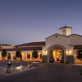 A beautifully designed building illuminated at night, showcasing elegant architecture and a serene fountain.