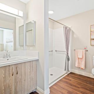 A modern bathroom featuring a sink with a mirror, a glass-enclosed shower, and wooden flooring.