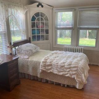 A cozy bedroom with a single bed, white bedding, and abundant natural light.