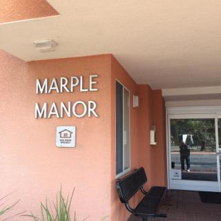 Entrance to Marple Manor with a bench and signage.