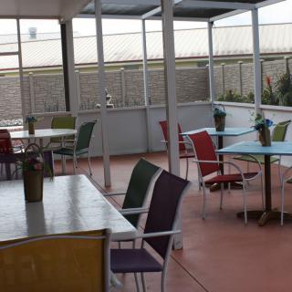 An outdoor patio area with empty tables and colorful chairs.