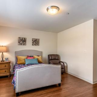 A cozy bedroom with modern decor featuring a stylish bed, nightstand with lamp, and comfortable seating.