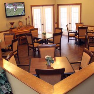 A cozy dining area with wooden tables and chairs, featuring a television mounted on the wall.