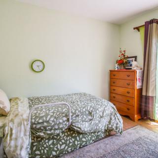 A cozy bedroom with a bed, dresser, and window with curtains.